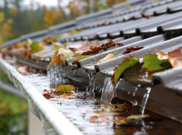 Rainwater overflowing from a clogged white gutters